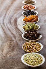 Group of indian spices in bowls on wooden background