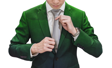Young businessman in green suit tying grey necktie, isolated on white background