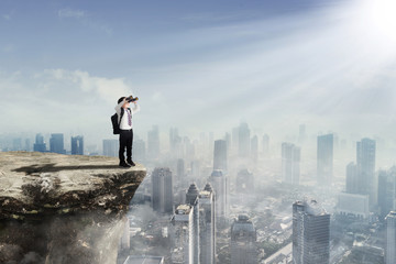 Little boy using binoculars on the cliff