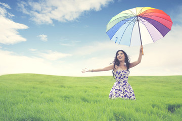 Beautiful young asian woman with umbrella on green field.