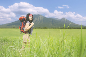 Happy hiker is standing in the meadow