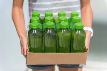 Photo sur Plexiglas Jus Boîte de bouteilles de jus de smoothie vert de jus de légumes pressés à froid. Femme tenant la boîte de livraison. Tendance santé pour le nettoyage des jus crus biologiques. Jus pour régime détox.