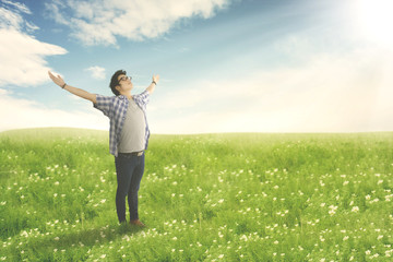 Happy man with arms wide open enjoying spring on blossom meadow.