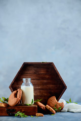 Healthy breakfast concept with oatmeal cookies, a bottle of milk, a wooden tray and pistachio leaves on a light gray stone background. Tasty homemade pastry concept with copy space.