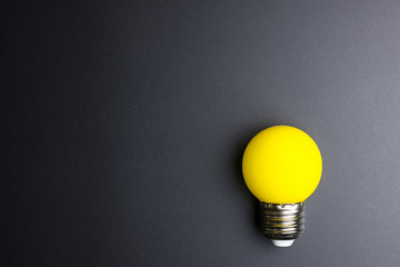 Yellow light bulb on black background with copy space.
