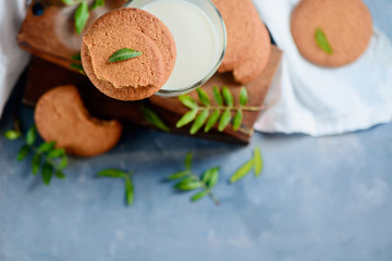 Fototapeta na wymiar Homemade cookies with tiny green leaves decor on a stone background with wooden boxes and white linen napkin. Spring baking flat lay with copy space.