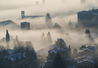 Fototapeta premium Bergamo, Italy. Drone aerial view of an amazing landscape of the fog rises from the plains and covers the old town
