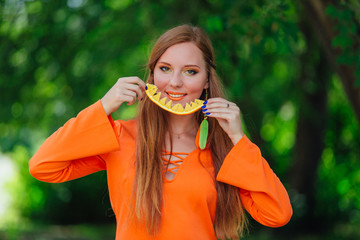 Portrait of pretty red hair woman with juicy delicious orange at summer green park.