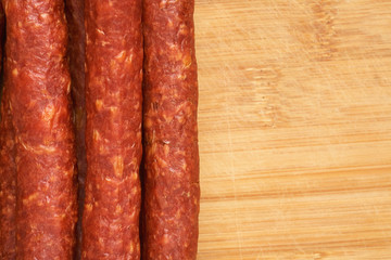 Thin smoked sausage on a wooden background. Close-up.