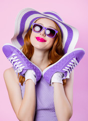 girl in sunglasses and hat holding shoes