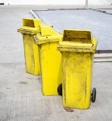 Old yellow trash bin on the street.