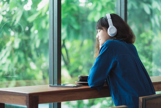 Happy Asian Casual Woman Listening Music With Headphones Near Window At Cafe Restaurant,Digital Age Lifestyle,chill Out Life.