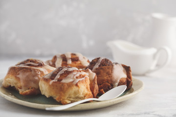 Homemade cinnamon buns in glaze on a light plate, light background, copy space. Breakfast concept.