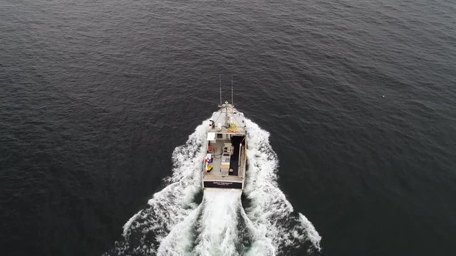 Aerial of a fishing boat while checking their lobster traps in ocean