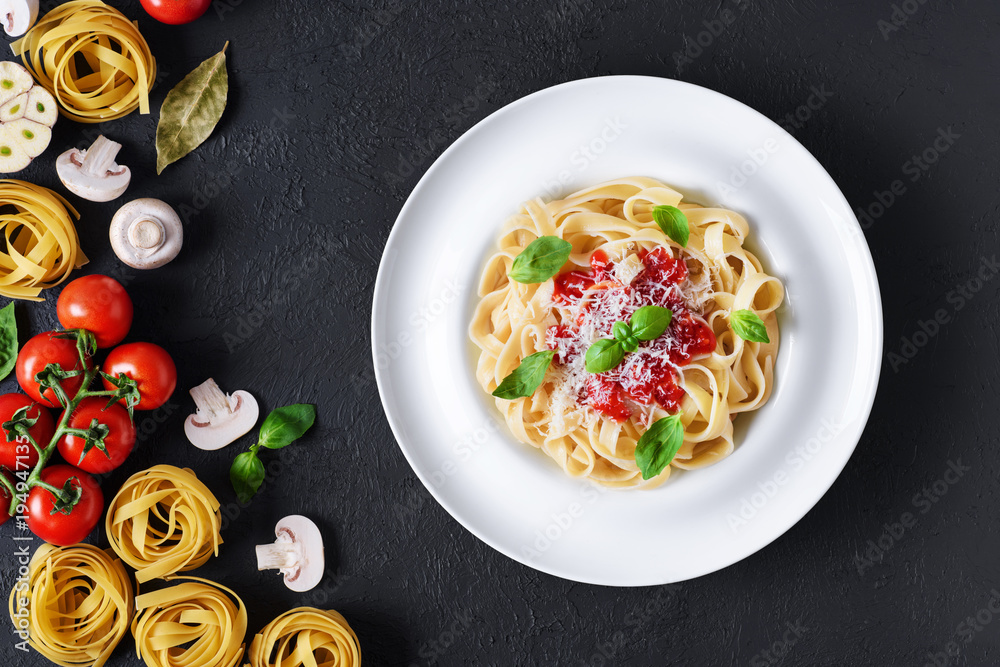 Wall mural ingredients for tagliatelle pasta on a dark background. plate with pasta.