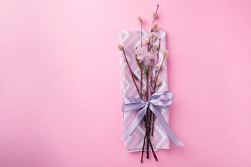 Napkin with satin ribbon willow branch of a flower, for serving an Easter table on a trendy pink background.