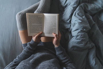 Obraz premium woman read book in bed with grey sheets
