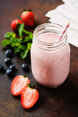 Pink berry smoothie in jar on dark background, closeup view, selective focus. Healthy lifestyle, detox, dieting, clean eating, vegan, fitness, vegetarian concept