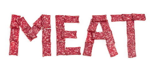 Word MEAT laid out with sausage slices on white background