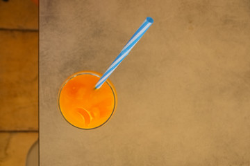 Fresh orange juice with ice cubes and swizzle stick isolated on table, top view. Selective focus. Summer refreshing drink. Salvation from thirst. Copy space