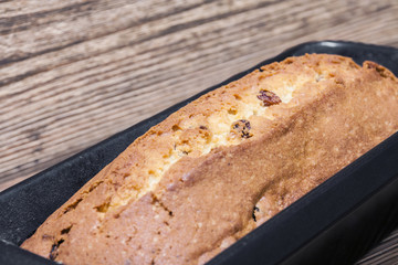 Homemade rectangular traditional cupcake with raisins in baking dish on the brown wooden background. Closeup, selective focus