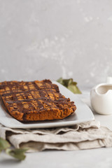 Vanilla vegan aquafaba cake with chocolate glaze in a white dish. Healthy vegan food concept.