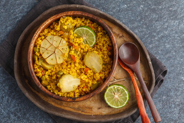 Curry bulgur with vegetables in wooden bowl. Dark background, top view, vegan meal concept.