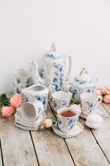 tea set in composition with flowers and marshmallows. Coffee mug on a saucer, a teapot and a sugar bowl. Filmed in the interior