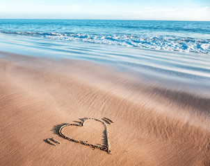 heart drawn in the sand on the shore of the ocean, the concept of a love of travel