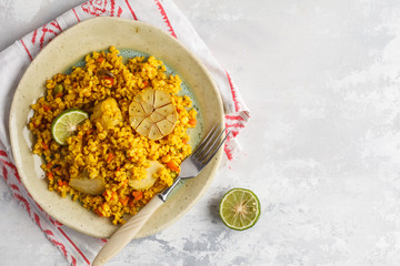 Curry bulgur with vegetables in white plate, top view, copy space. Healthy vegan food concept.