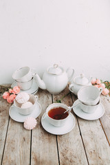 tea set in composition with flowers and marshmallows. Coffee mug on a saucer, a teapot and a sugar bowl. Filmed in the interior