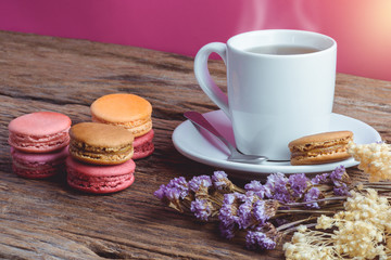 Obraz na płótnie Canvas Different types color of macaroons with Cup of hot tea on Old grunge wooden background