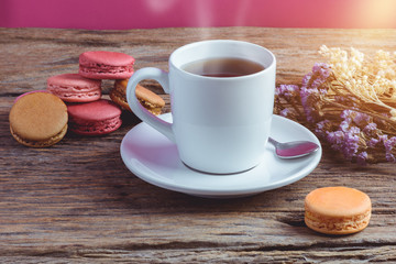Different types color of macaroons with Cup of hot tea on Old grunge wooden background