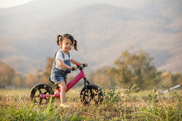 Happy child riding a bike. Little girl on a pink bicycle. Healthy preschool children summer...