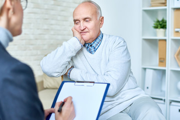 Portrait of balding senior man talking to female therapist during consultation, copy space