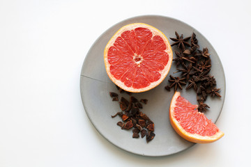 Ripe grapefruit slices and heap of star anise spices isolated on grey concrete plate from a high angle view