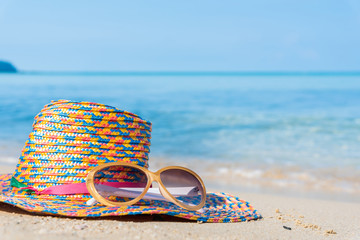 sunglasses and straw hat with blur blue sea and sky background - holiday concept