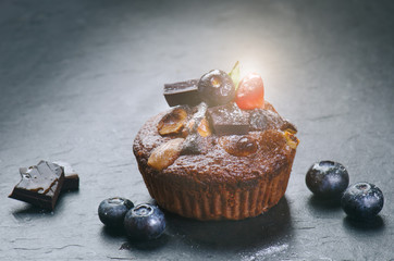 Fresh, blueberry muffins with strawberry, chocolate on a stone background with sugar and fruits. Food background. Concept of pastry.