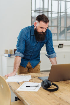 Modern casual businessman standing at his desk