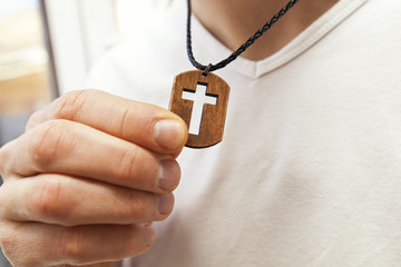 The wooden cross necklace on man's neck