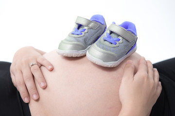 pregnant woman with baby shoes on her belly