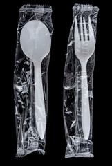 Plastic spoon and fork in clear bag on black background