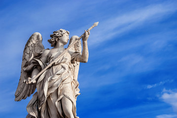 Fototapeta na wymiar Angel holding the Holy Lance of Longinus (with beautiful sky and copy space). A 17th century baroque masterpiece at the top of Sant'Angelo Bridge in the center of Rome