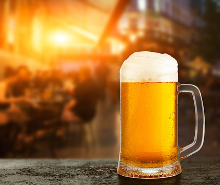 Mug with beer on the background of a outside bar.