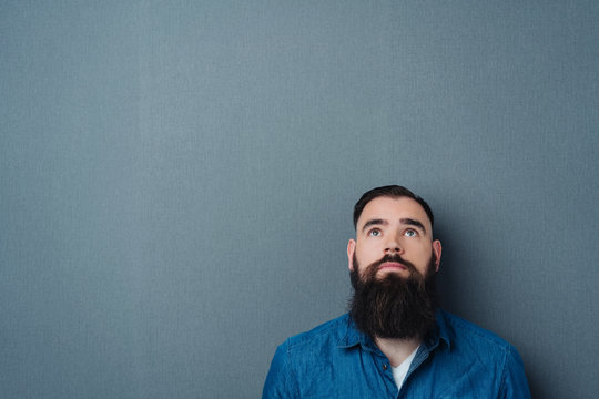 Bearded young man looking up to blank copy space