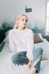 Obraz premium Cute girl on a comfortable chair with tea ,reading a book, the concept of comfort and hipster