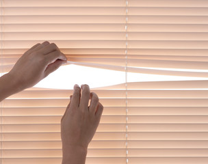 Windows jalousie,hand separating slats of venetian blinds with a finger to see through