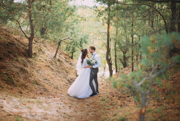 Groom hugging his laughing bride in green park