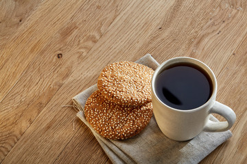 Porcelain teacup with chocolate chips cookies on cotton napkin on a rustic wooden background, top view