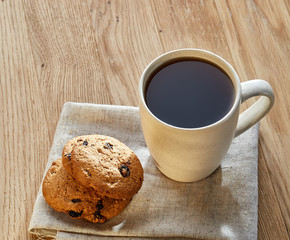 Porcelain teacup with chocolate chips cookies on cotton napkin on a rustic wooden background, top view